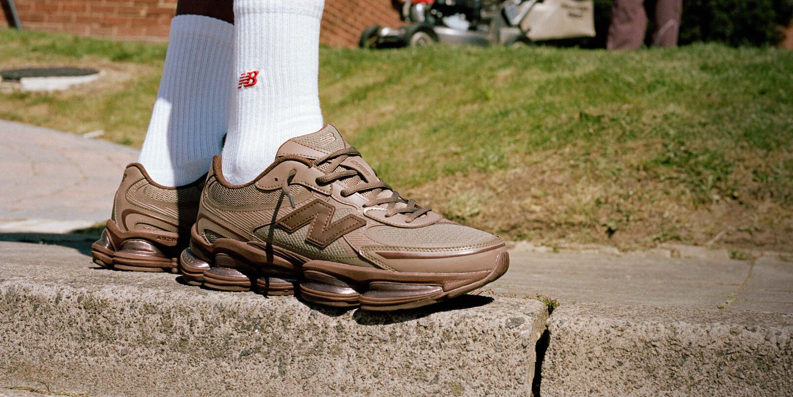 Knee-down image of someone wearing brown New Balance sneakers outdoors.